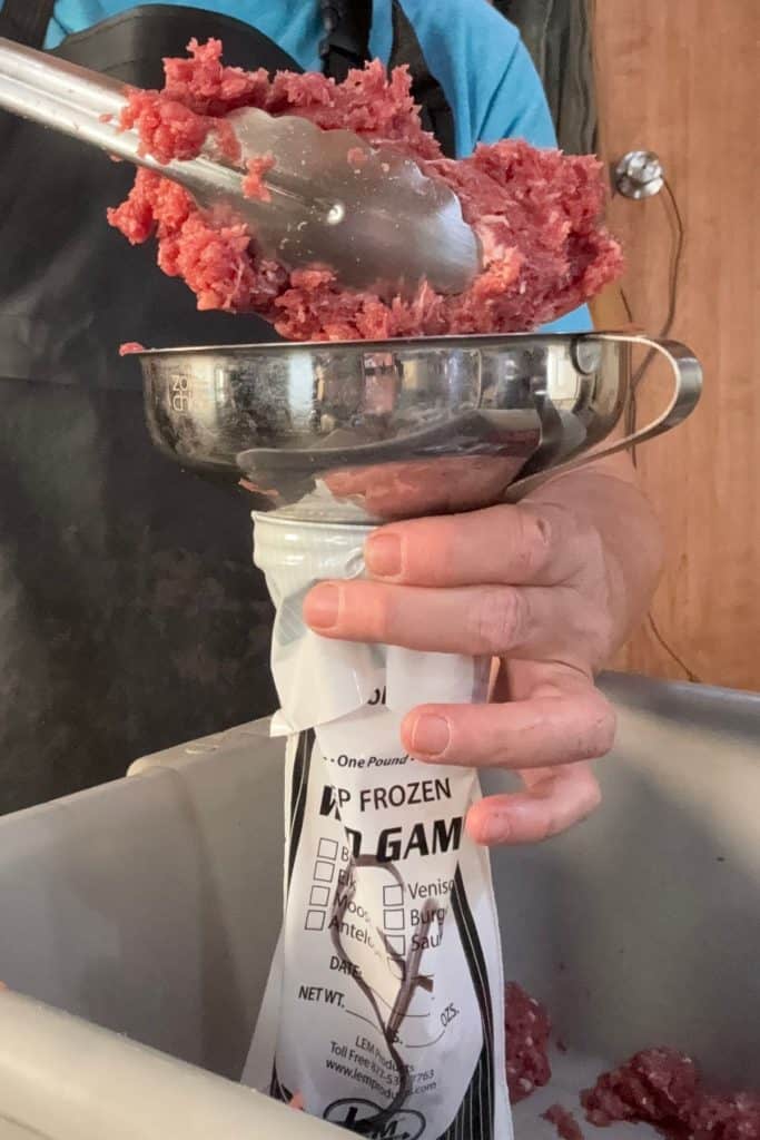 using a canning funnel and tongs to fill the game bag