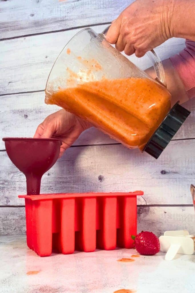using a funnel to direct the fruit mixture